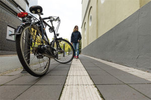 Halte Leitstreifen frei: Ein Fahrrad parkt nahe eines Leitsystems. Sein Vorderreifen ragt einige Zentimeter über die taktilen Bodenplatten