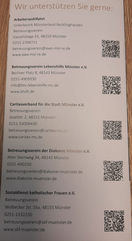 Ein gedrucktes Faltblatt mit Kontaktinformationen und QR-Codes für verschiedene soziale Einrichtungen in Münster, Deutschland.