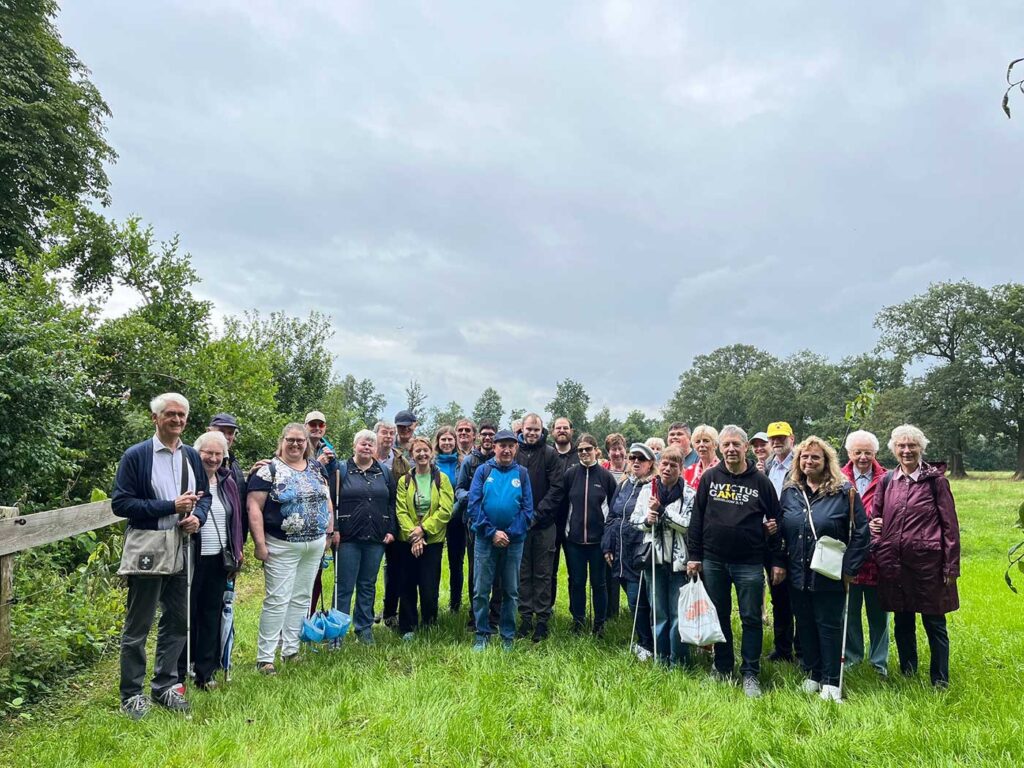 Gruppenbild mit 30 Personen,von denen einige einen Blindenlangstock halten, stehen auf einer Wiese. Im Hintergrund sind mehrere Bäume zu sehen.